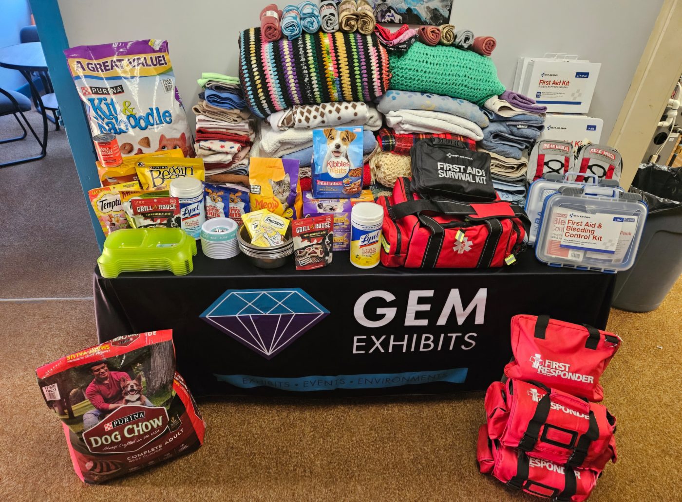 Table draped with a GEM Exhibits cloth, covered in donated blankets, pet food and supplies