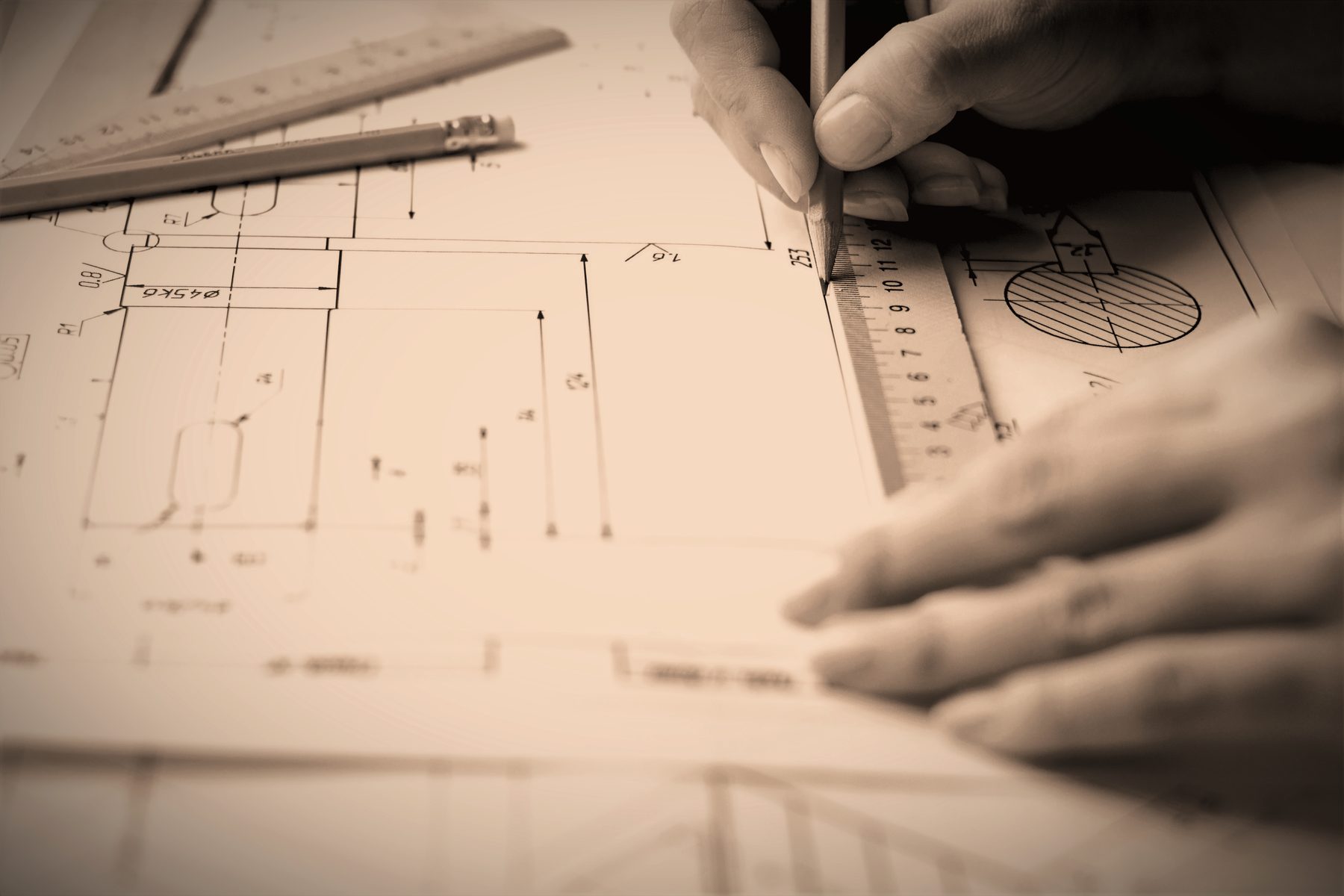 Hands drafting an exhibit layout over a technical drawing