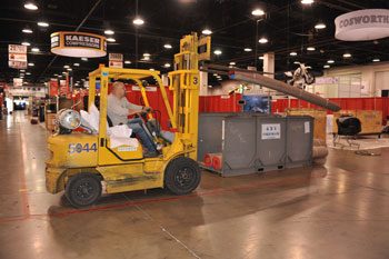 Forklift moving a crated exhibit through a convention centre aisle