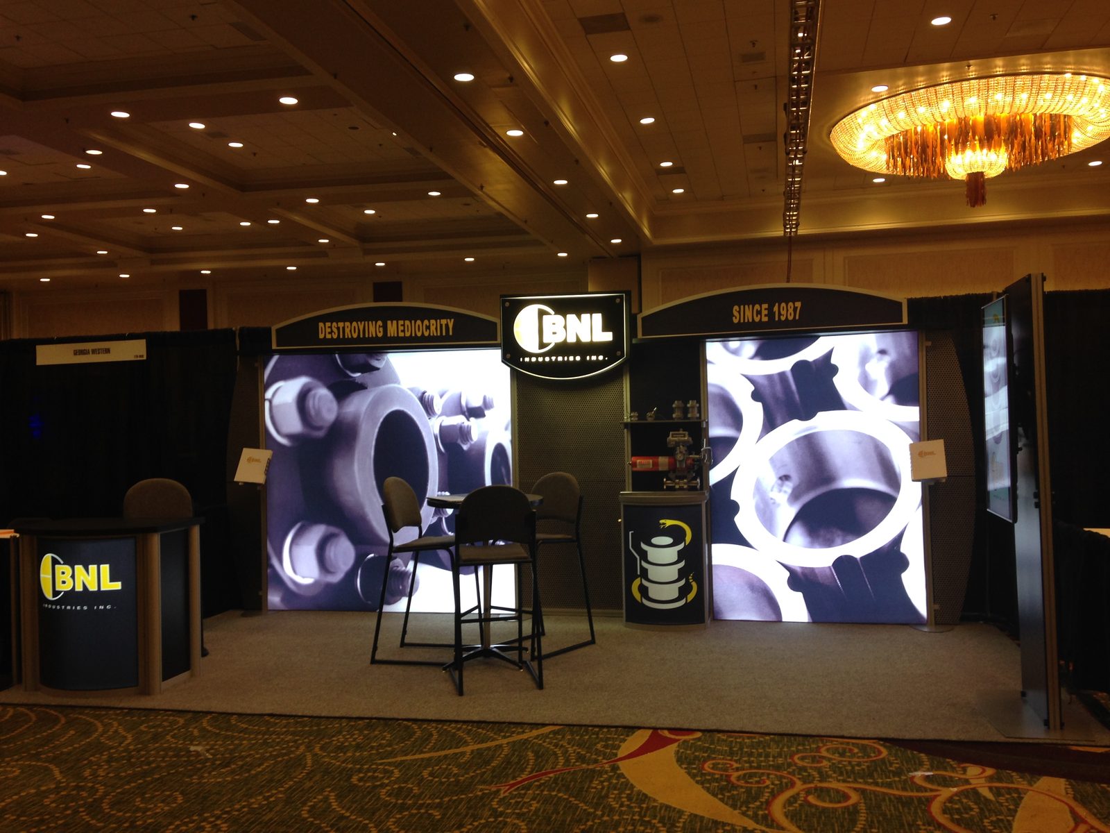 Island exhibit with illuminated lightbox graphics and bar seating