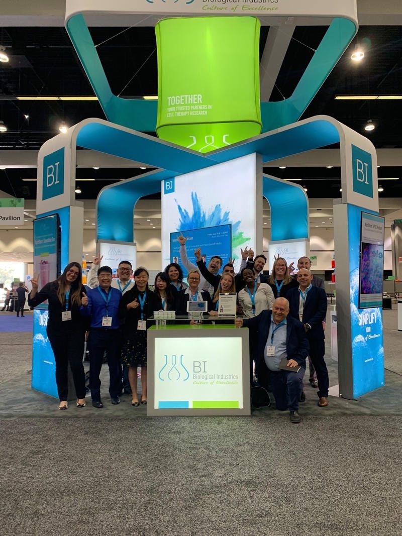 Team gathered in front of a green and blue island exhibit with a tall overhead ring