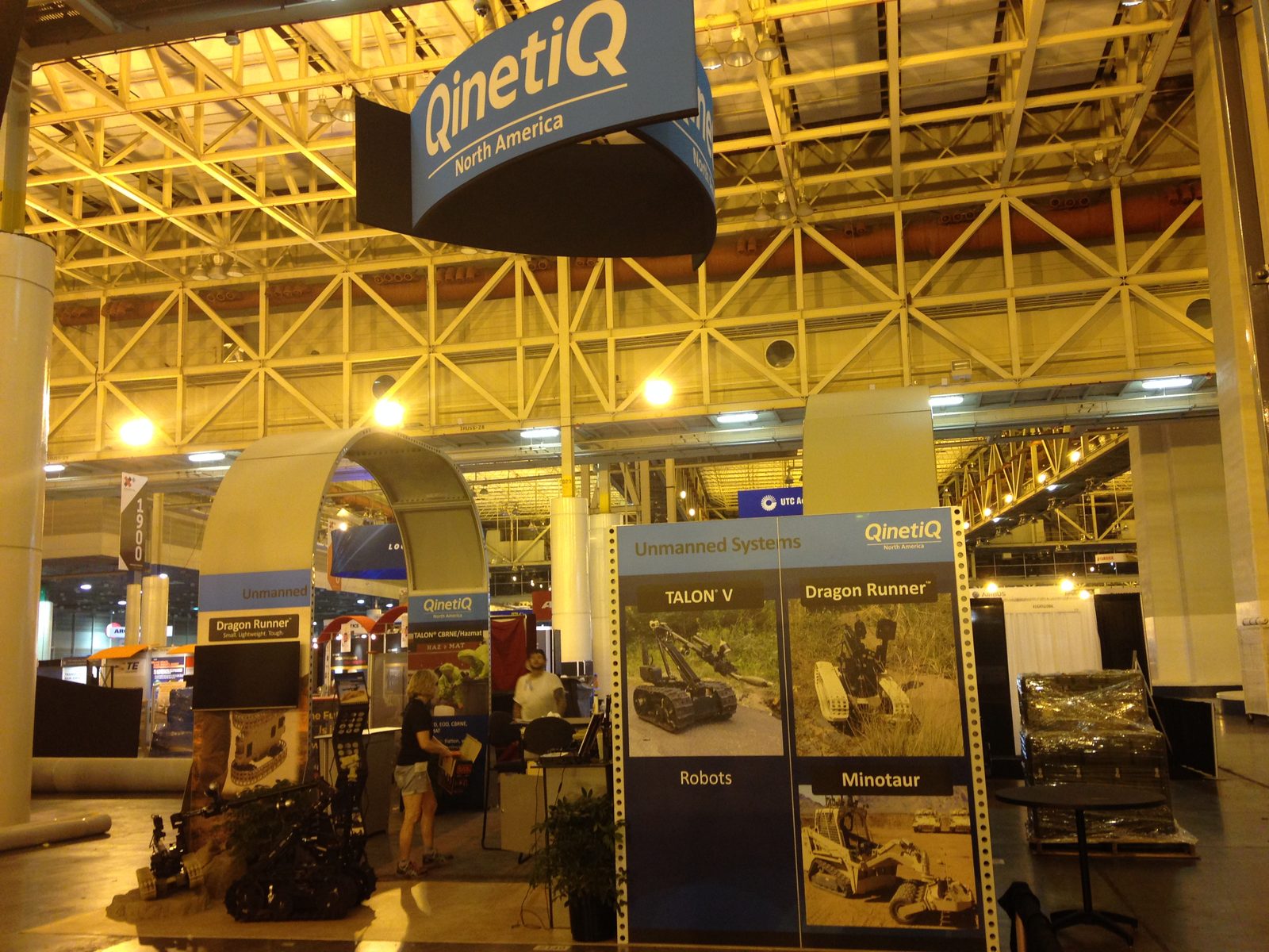 Large custom exhibit structure with an overhead arch on a busy show floor